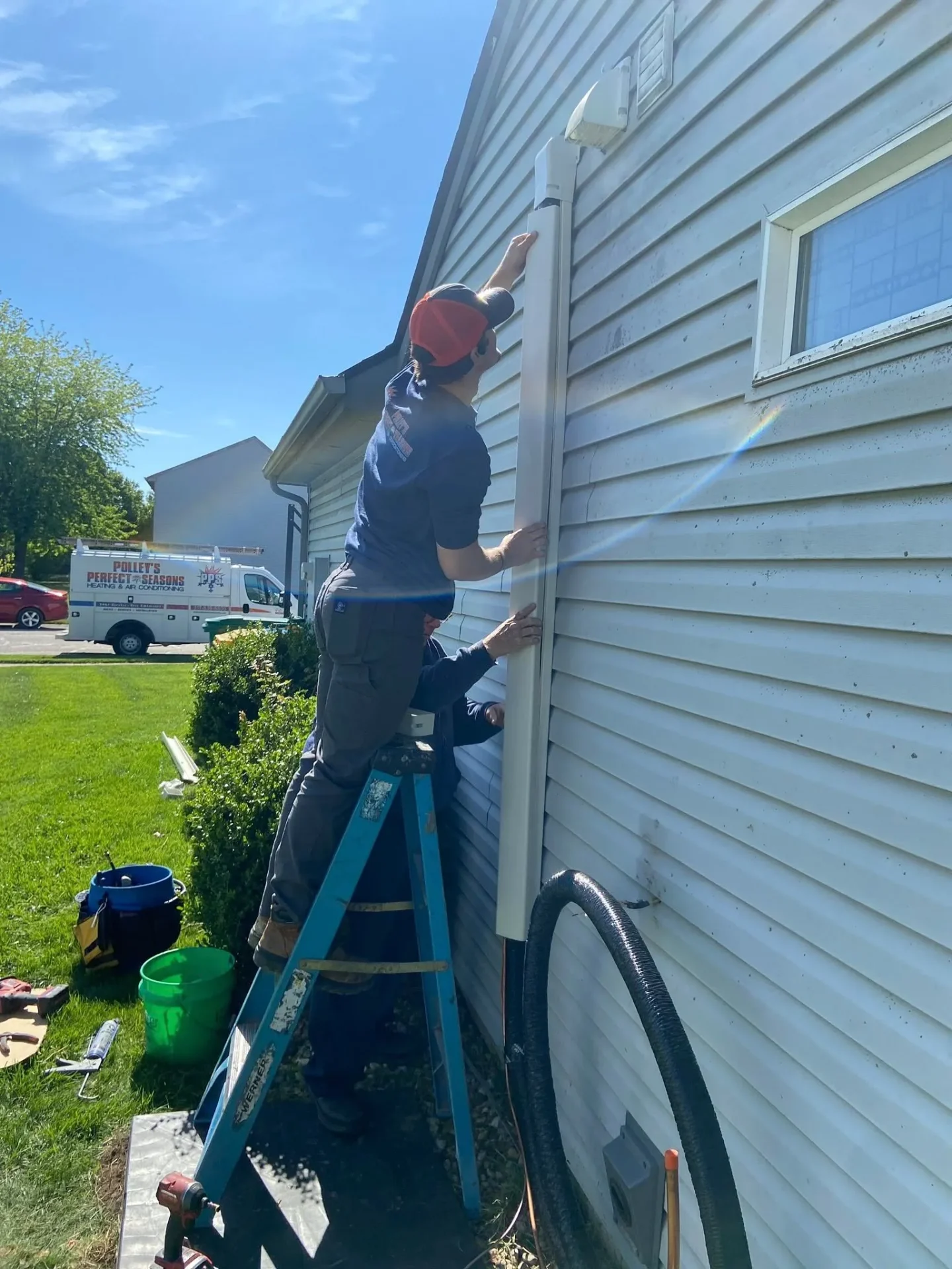 Polley's Perfect Seasons technicians installing a clean exterior line-set cover on an AC install in Plainfield, IN