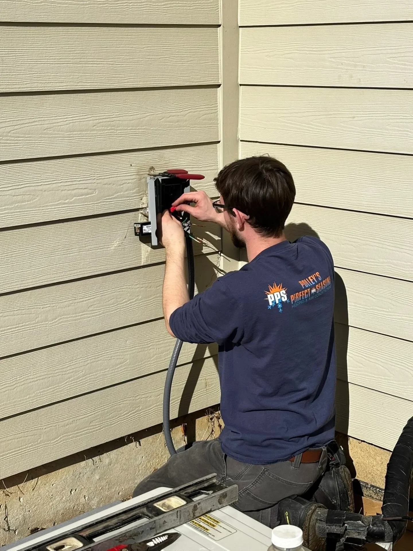 Polley's Perfect Seasons technician wiring the exterior disconnect for a new AC install in Plainfield, IN