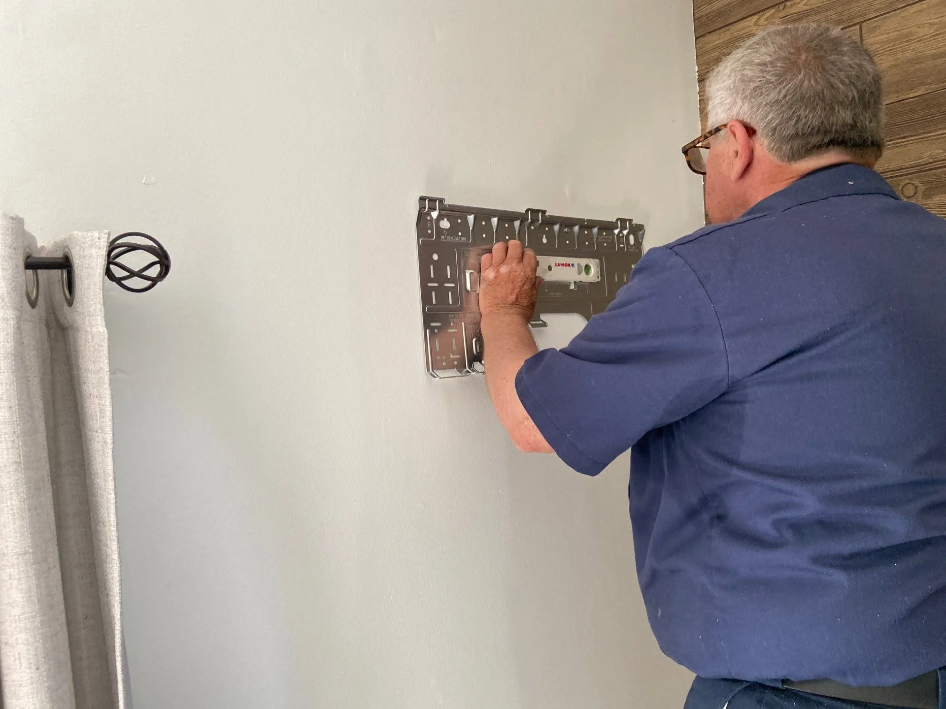 Technician leveling the wall bracket for a ductless mini split indoor air handler in a Hendricks County home