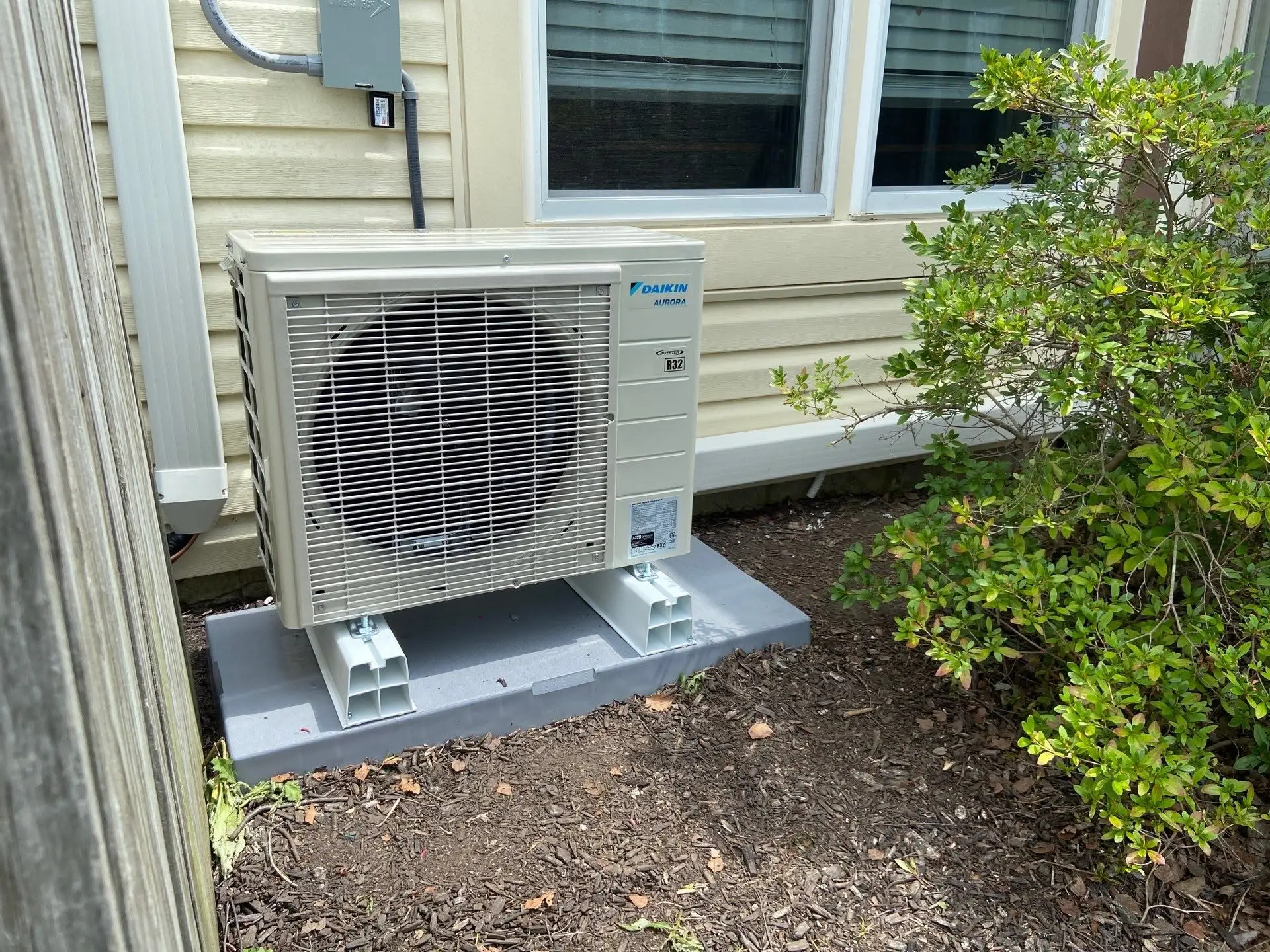 Daikin Aurora R32 ductless mini split outdoor unit installed on a composite pad beside a Hendricks County home