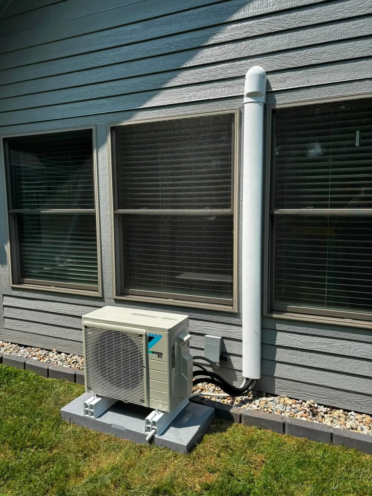 Daikin ductless mini split outdoor unit on a pad with line set cover running up the siding of a home in Avon, Indiana