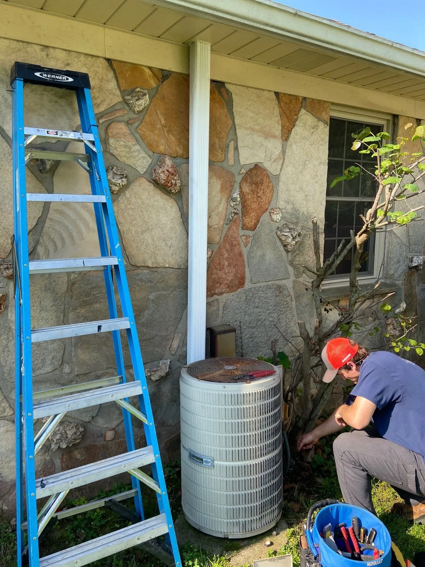 Polley's Perfect Seasons technician disconnecting an aging outdoor air conditioner at a stone home before a ductless mini split install
