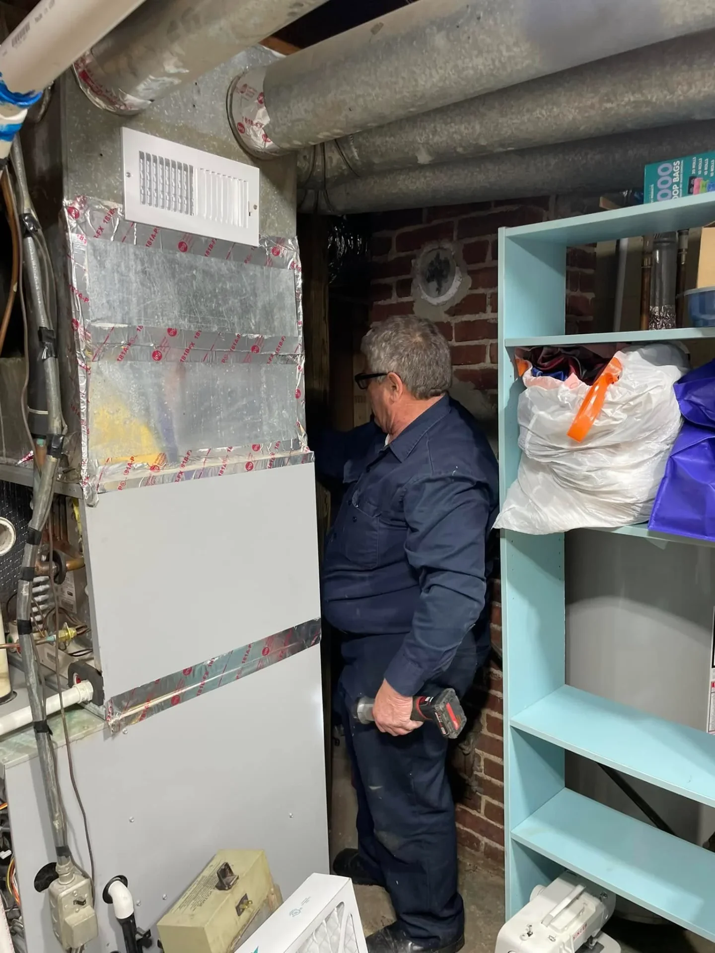 Polley's Perfect Seasons technician working on basement ductwork during a duct cleaning and repair in Plainfield, IN