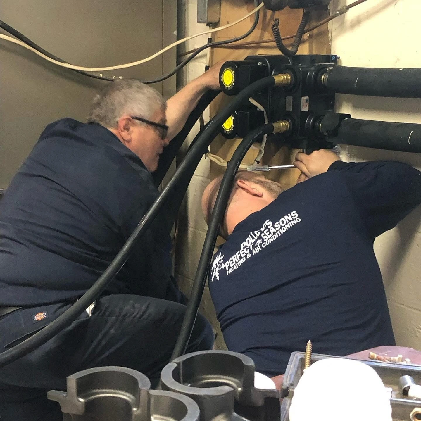 Two Polley's Perfect Seasons technicians rebuilding a hydronic manifold on a Brownsburg, IN service call